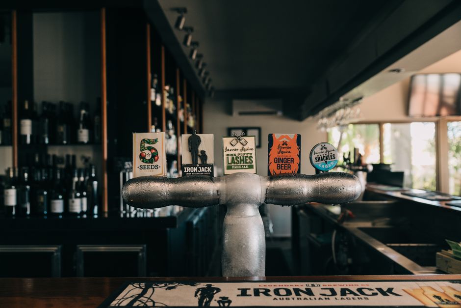 Close-up of beer tap handles at a modern pub bar counter showcasing various brands.