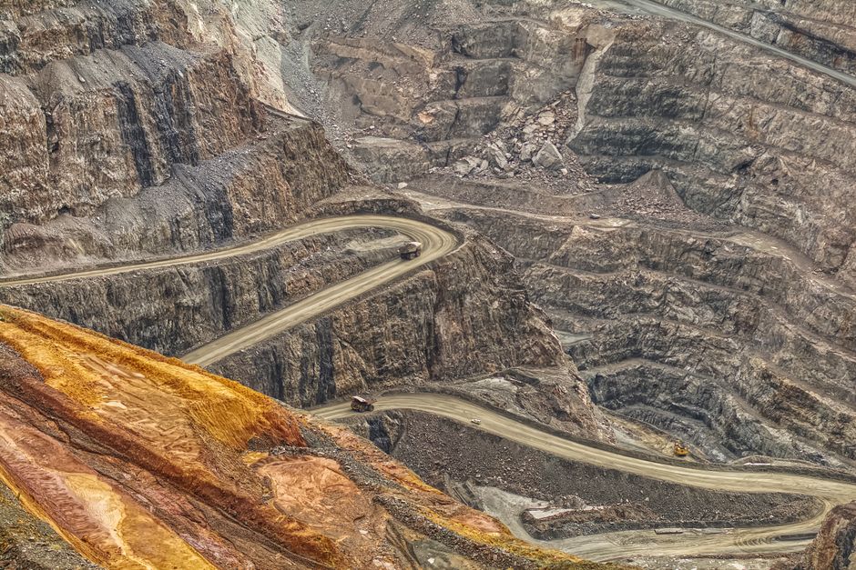 Dramatic aerial shot of winding roads in a massive open-pit mine, showcasing earth textures.