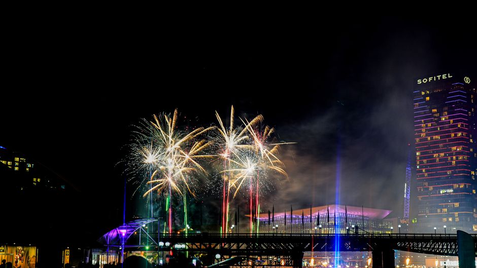 Vibrant fireworks illuminate the night sky over a bustling cityscape, creating a stunning visual display.