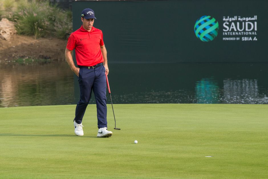 A male golfer in red shirt on a golf course at Saudi International event.