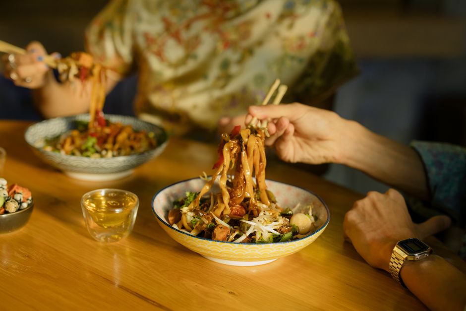 Close-up of delicious Asian noodles served with chopsticks in a cozy restaurant setting.